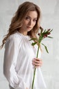 Portrait of a sexy charming woman in a white blouse with a flower in her hands