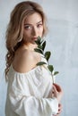 Portrait of a sexy charming woman in a white blouse with a flower in her hands