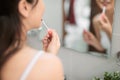 Portrait of sexy concentrated young woman standing at mirror and applying lipstick or lip gloss. Beauty and routine concept Royalty Free Stock Photo