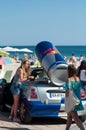 Portrait of sexy girls with jeans short and white teeshirt giving fresh red bull cans on the beach