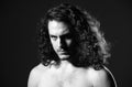 Portrait of sexy handsome guy with curly hair. Macho brutal guy with long curly isolated on gray background.