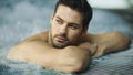 Portrait of sexy man enjoying in whirlpool bath. Handsome guy relaxing in pool