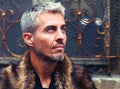 Portrait of a man in wolf fur and ornamental medieval windowPortrait of a man in wolf fur and ornamental medieval wind Royalty Free Stock Photo