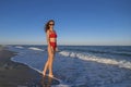 Portrait of sexy woman in red swimsuit. Girl takes sunbath on empty sea shore before sunset Royalty Free Stock Photo