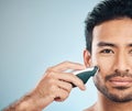 Portrait, shaving and electric razor with a man in studio on a blue background for personal hygiene or grooming. Face Royalty Free Stock Photo