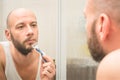 A portrait of a shaving guy settles in the mirror. A man shaves in front of the mirrors in the bathroom. The young man tidies Royalty Free Stock Photo