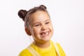 Portrait of shining little kid showing missing front baby tooth and smiling looking away in yellow t-shirt on white