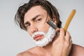 portrait of shirtless man with foam on face shaving beard with straight razor Royalty Free Stock Photo