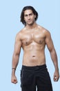 Portrait of shirtless young muscular man standing over blue background Royalty Free Stock Photo