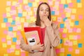 Portrait of shocked amazed astonished young adult woman holding paper folders with documents, covering mouth with palm, working in Royalty Free Stock Photo