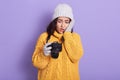 Portrait of shocked attractive emotional brunette holding photocamera in one hand, looking through photos, unsatisfied with