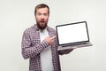 Portrait of shocked bearded man holding laptop and pointing at empty screen. isolated on white background Royalty Free Stock Photo