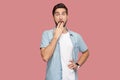 Portrait of shocked bearded young man in blue casual style shirt standing with big eyes, covering his mouth and looking at camera Royalty Free Stock Photo