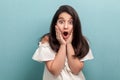 Portrait of shocked beautiful brunette young girl with black long straight hair in white dress standing and looking at camera with Royalty Free Stock Photo