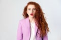 Portrait of shocked beautiful business woman with red - brown hair and makeup in pink suit. looking at camera