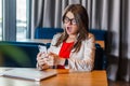 Portrait of shocked beautiful stylish brunette young woman in glasses sitting, holding mobile smart phone and looking at screen Royalty Free Stock Photo