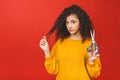 Portrait of shocked curly girl cutting her hair with scissors, isolated on red background Royalty Free Stock Photo