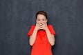 Portrait of shocked frightened girl covering mouth with both hands