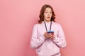 Portrait of shocked funny teenage girl in casual hoodie looking at cellphone screen with opened mouth, expensive price, mobile app Royalty Free Stock Photo