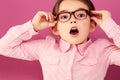 Portrait, shocked and girl child with glasses in studio isolated on a pink background. Kid, nerd and face of surprised Royalty Free Stock Photo