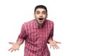 Portrait of shocked handsome bearded man in red checkered shirt standing and looking at camera with amazed face, big eyes, open Royalty Free Stock Photo