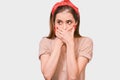 Portrait of shocked horrified young woman covering mouth with hands feel scared looking away, isolated on white studio wall. Royalty Free Stock Photo