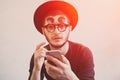Portrait of shocked man with smartphone in hands, wearing hipster sunglasses and black hat, over white background, with Royalty Free Stock Photo