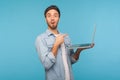 Man holding laptop and pointing at screen, surprised about computer application, internet news. Royalty Free Stock Photo