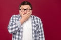 Portrait of shocked middle aged business man in casual checkered shirt and eyeglasses standing, covering his mouth and looking at Royalty Free Stock Photo