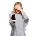 Portrait of shocked woman covering her eyes with hand showing mobile phone blank screen isolated over white. Shocking news. Royalty Free Stock Photo