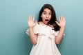 Portrait of shocked or scared beautiful brunette young girl with black long straight hair in white dress standing with hand block Royalty Free Stock Photo