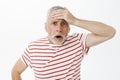 Portrait of shocked speechless concerned old man punching forehead with palm with troubled look open mouth and looking