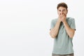 Portrait of shocked speechless handsome guy in casual t-shirt, covering mouth and staring with popped eyes at camera