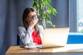 Portrait of shocked stylish brunette young woman in glasses sitting, looking at laptop screen on video call and reading Royalty Free Stock Photo