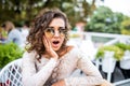 Portrait of shocked and surprised latin womanin sunglasses in cafe with amazed and afraid expression