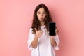 Shocked surprised little girl showing smart phone with black blank screen pointing finger at display Royalty Free Stock Photo