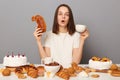 Portrait of shocked surprised woman with brown hair sitting at table isolated over gray background, looking at camera with big Royalty Free Stock Photo