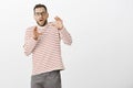 Portrait of shocked terrified adult european father in glasses and striped pullover, bending backwards with raised hands