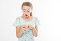 Portrait shocked young girl in dress looking at mobile phone isolated on white background