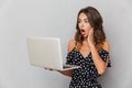 Portrait of a shocked young girl in dress over gray Royalty Free Stock Photo