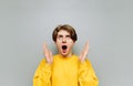 Portrait of shocked young man in bright clothes isolated on gray background, looking up with open mouth in surprise and arms Royalty Free Stock Photo