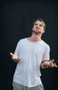 Portrait of a shocked young man spreading his arms at the dark wall Royalty Free Stock Photo