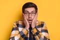 Closeup of amazed handsome guy in glasses isolated over yellow background