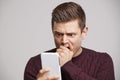 Portrait of a shocked young white man using a smartphone