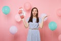 Portrait of shocked young woman in blue dress spreading hands holding red box with gift present on pink background with Royalty Free Stock Photo