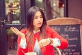 Portrait of shocked young woman holding hand with wrist watch and looking at camera isolated on coffee shop outside terrace Royalty Free Stock Photo