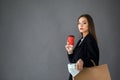 Portrait of shopaholic beautiful woman wearing suit holding money cash, cup of coffe and paper shopping bags isolated over grey