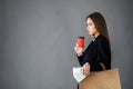 Portrait of shopaholic beautiful woman wearing suit holding money cash, cup of coffe and paper shopping bags isolated over grey