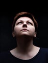 Portrait of short hair woman looking upward against black background