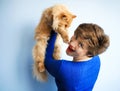 Portrait of short haired beautiful smiling 30 years old woman in blue dress playing with ginger red furry persian cat. Domestic Royalty Free Stock Photo